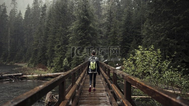 女性徒步旅行者走着通往森林的木