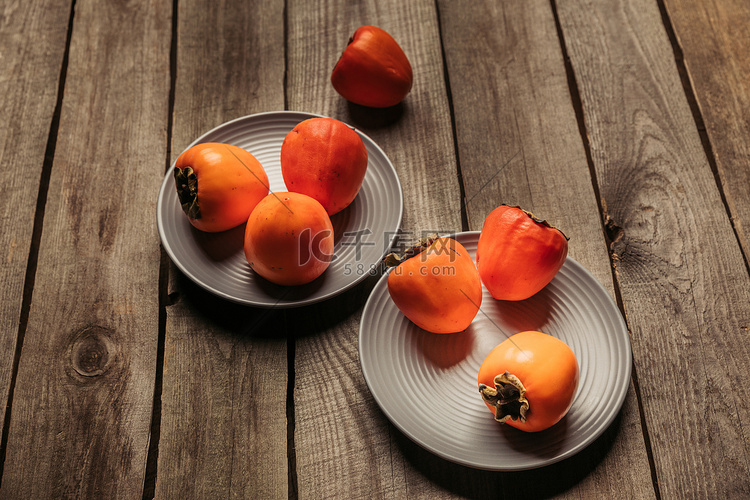 灰色木桌上的熟橙柿子