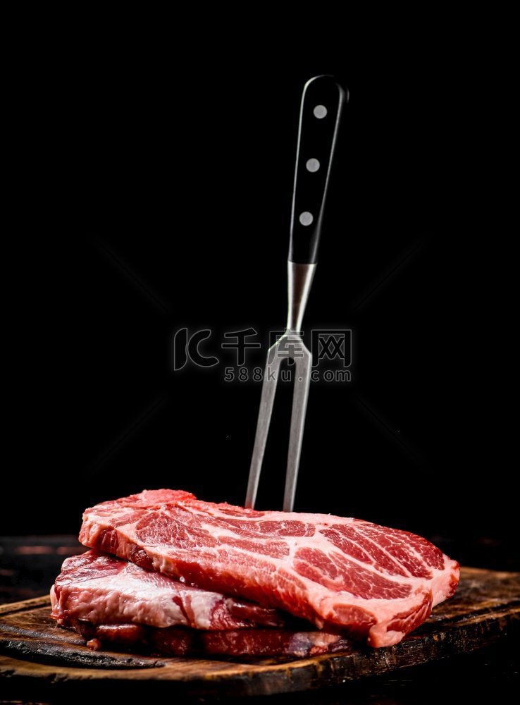 生猪排放在有叉子的菜板上。在黑