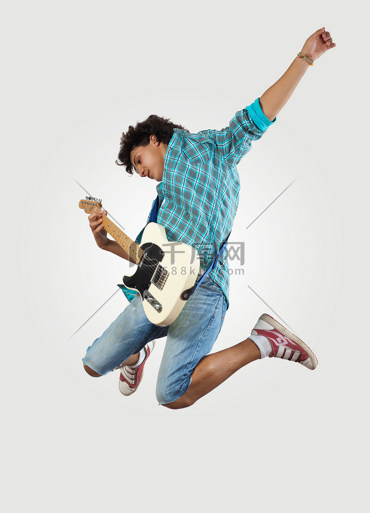 年轻人玩电吉他上和跳跃