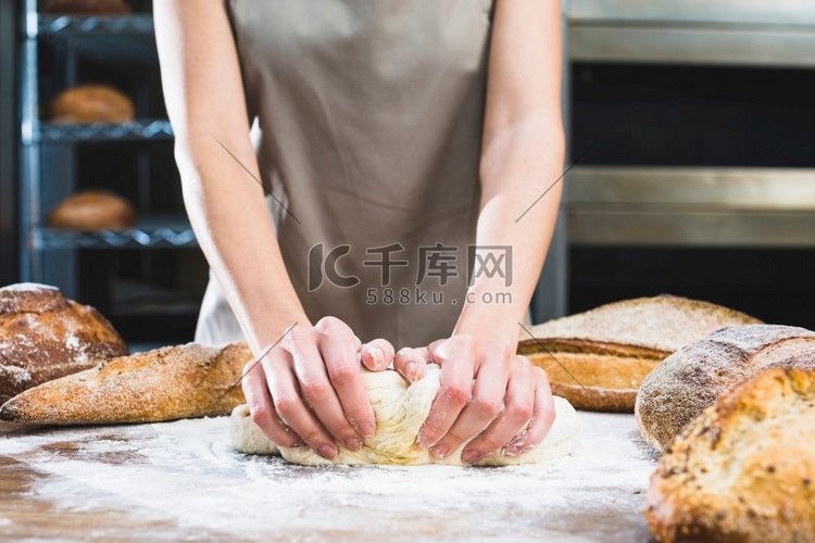 女面包师用面粉木面揉面团