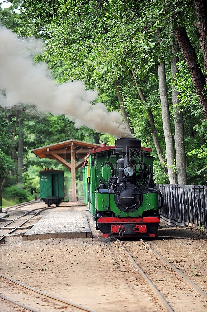 绿色的小老式蒸汽机车在轨道上行