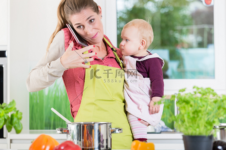妈妈在做饭和抱着婴儿的电话交谈