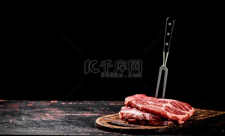 生猪排放在砧板上用叉子。黑色背