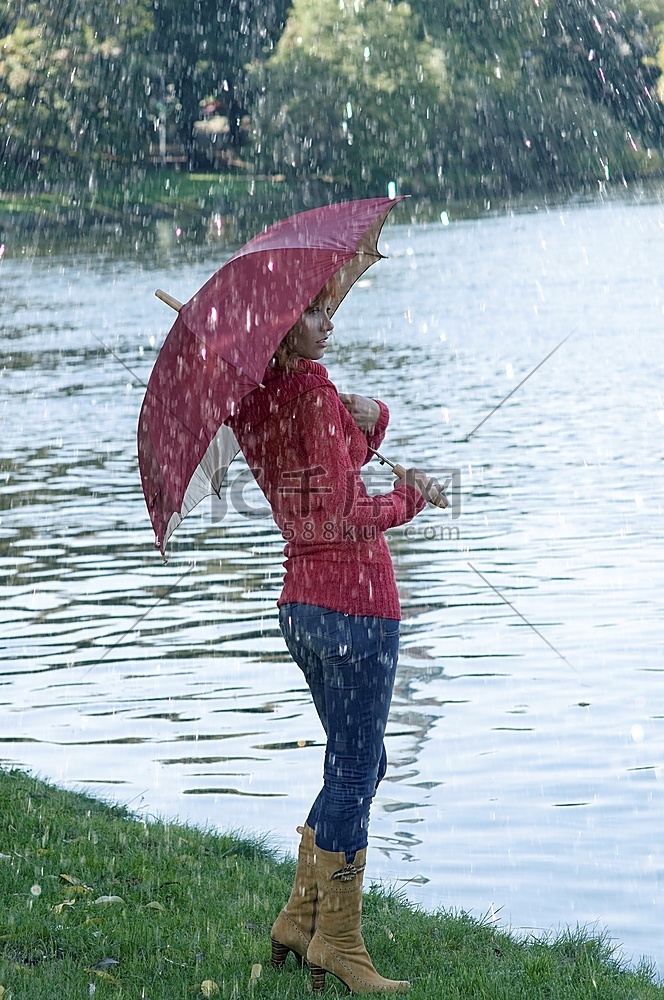 秋天里撑着伞望着河边的可爱女孩