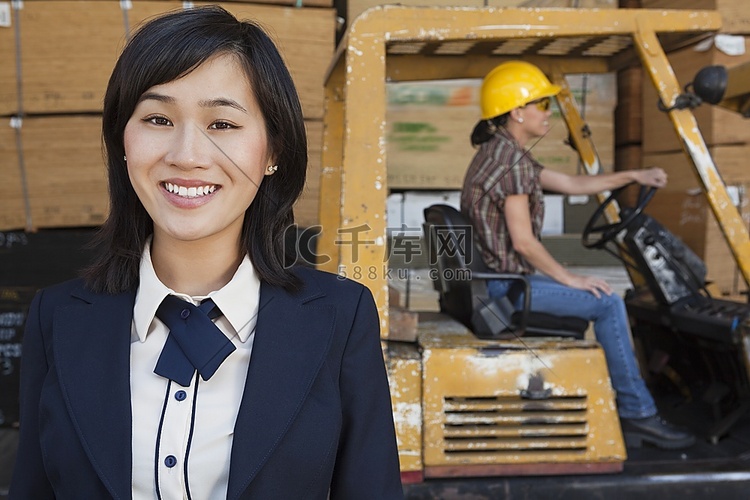 背景为女产业工人驾驶叉车时微笑