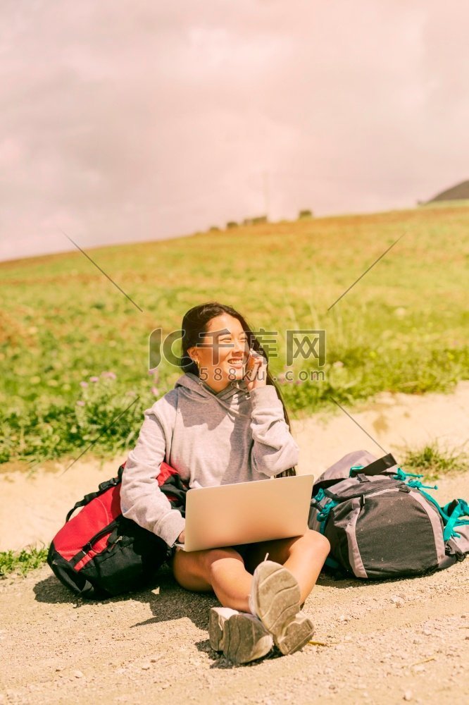 妇女坐在路上微笑说话的手机在背