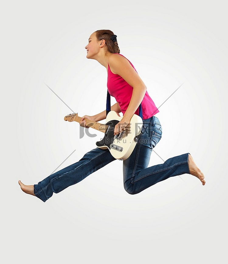 年轻女子玩电吉他和跳跃