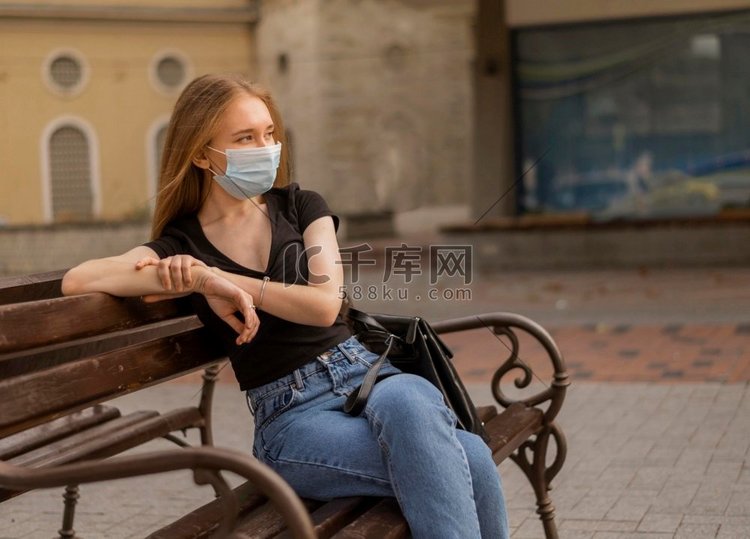 坐在长凳上的妇女戴着医用口罩