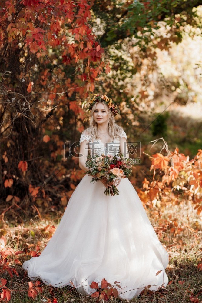 一件婚纱的金发女郎在秋天森林反