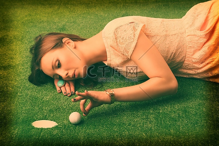 棕发美女躺在草地上玩高尔夫球的