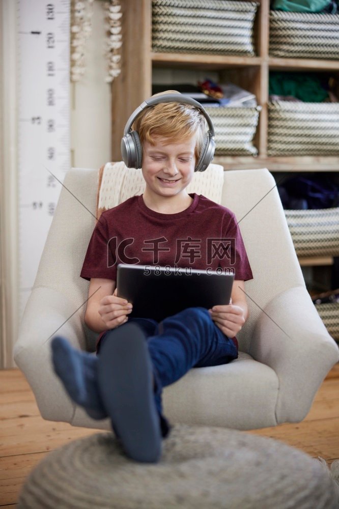 男孩坐在家里卧室的椅子上戴着耳