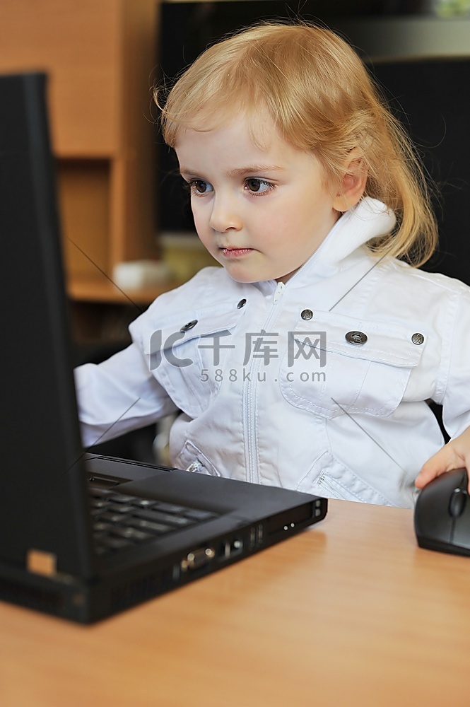 快乐的小女孩拿着笔记本电脑坐在