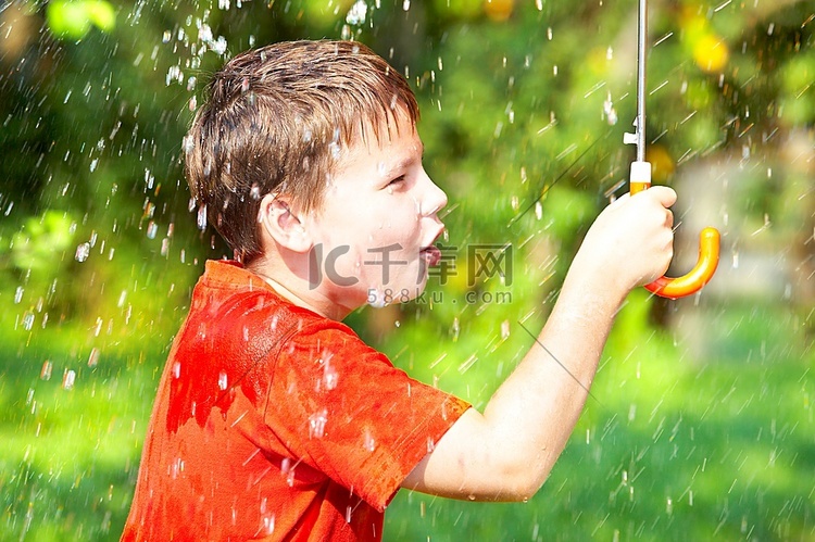 一个男孩在下雨时撑着伞..。