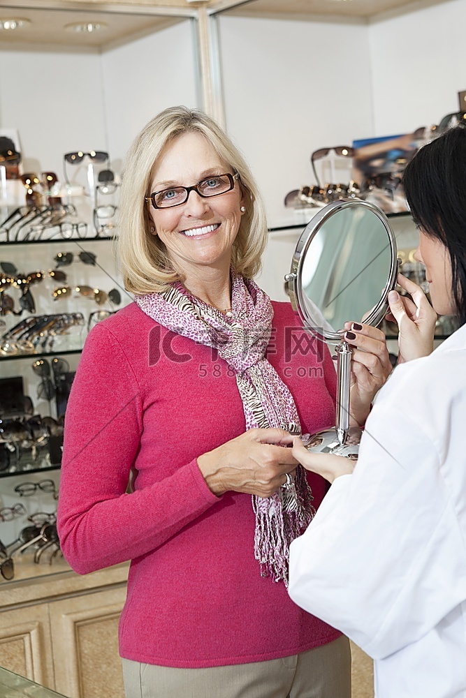 配镜师手持镜片时戴眼镜的老年妇