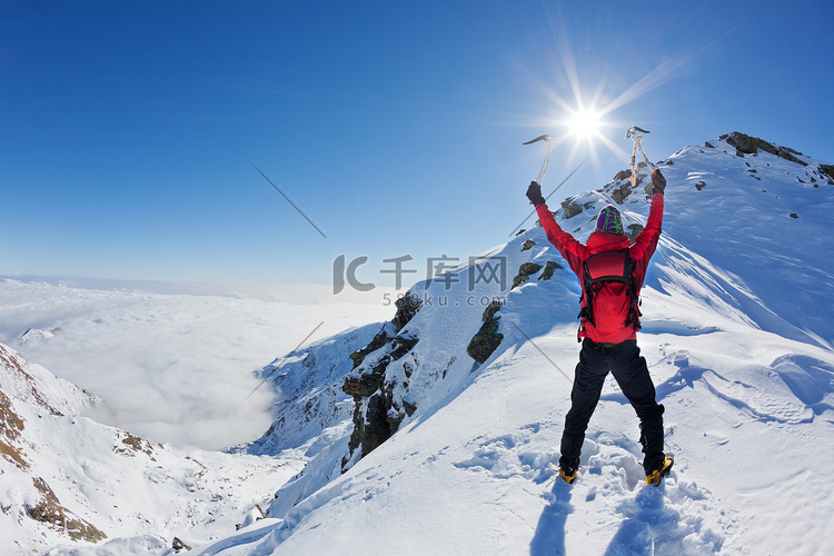 登山运动员到达顶部的雪山在阳光