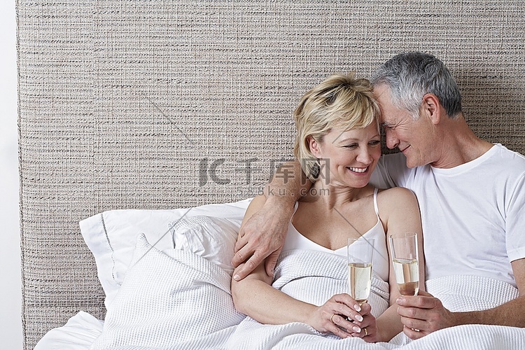 在床上喝香槟的中年夫妇
