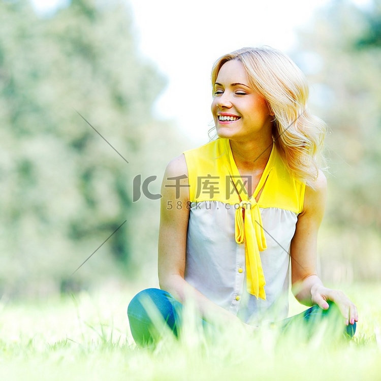 坐在草地上的美丽幸福的年轻女子