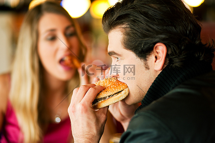 夫妇在餐馆或用餐者吃汉堡包和鸡