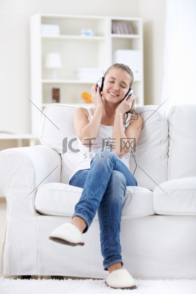 有魅力的女孩在家戴着耳机听音乐