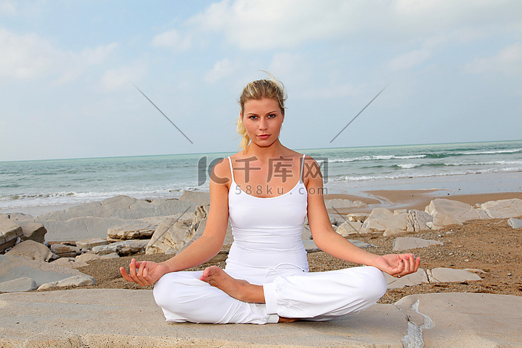 美丽的金发女子在海滩上练习瑜伽