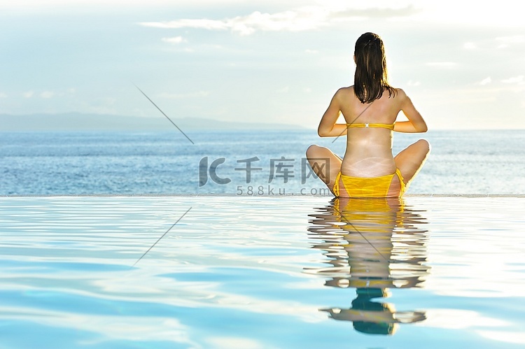 一名女子在泳池边做瑜伽锻炼