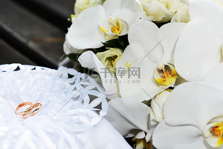 新娘枕头上的白色兰花和结婚戒指