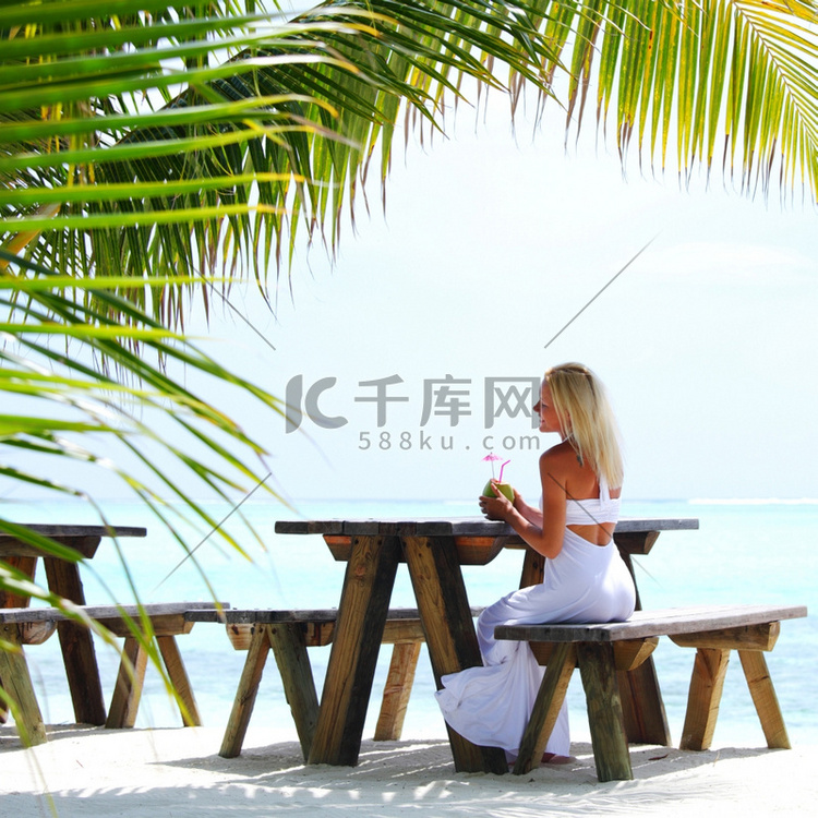 一个女人坐在一个热带咖啡馆在棕