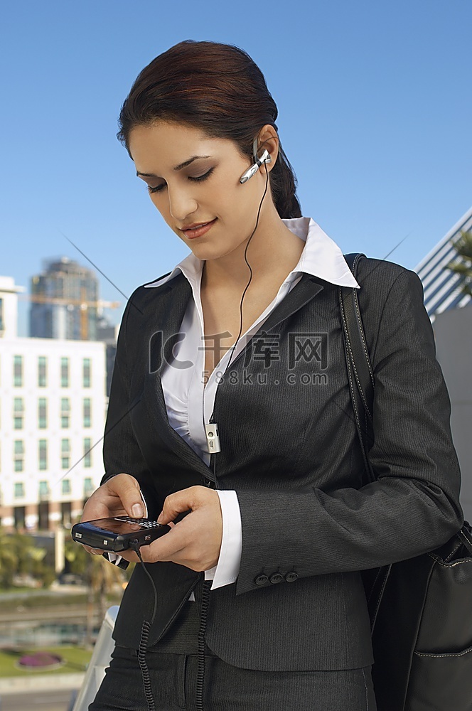 女商人戴着耳机，发短信，在户外