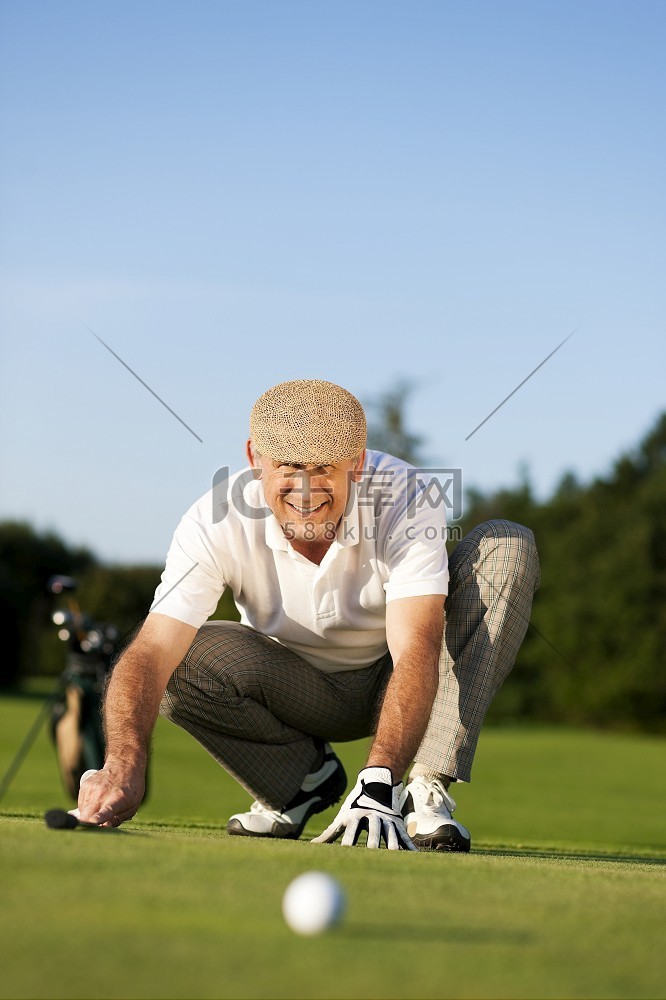 高年级男子打高尔夫球瞄准球洞，