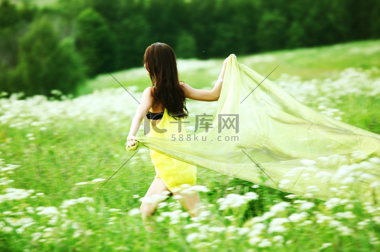 女孩在田野中奔跑，手中的布料像
