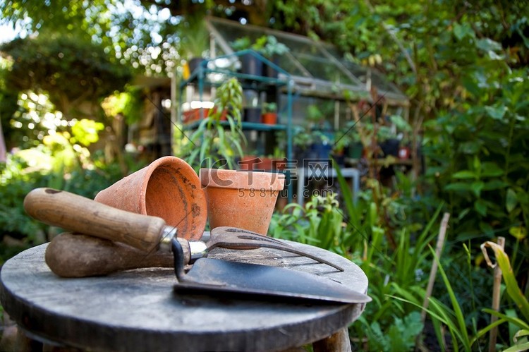 园艺用具和花盆放在绿色花园的凳
