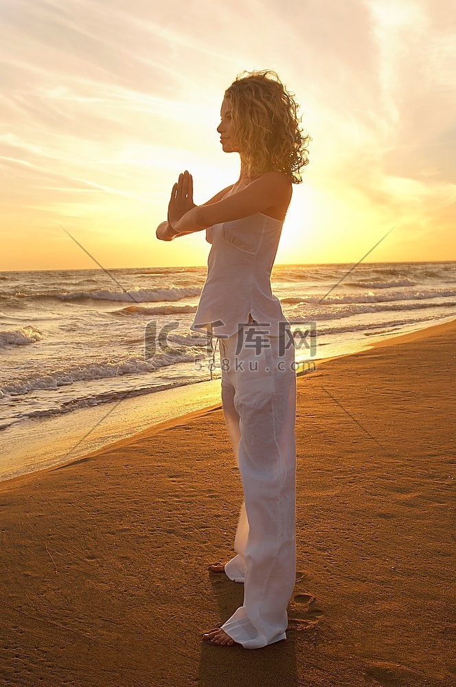 一名年轻女子在海滩上打太极，侧