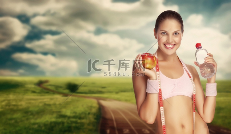一个年轻的女运动员拿着水和苹果