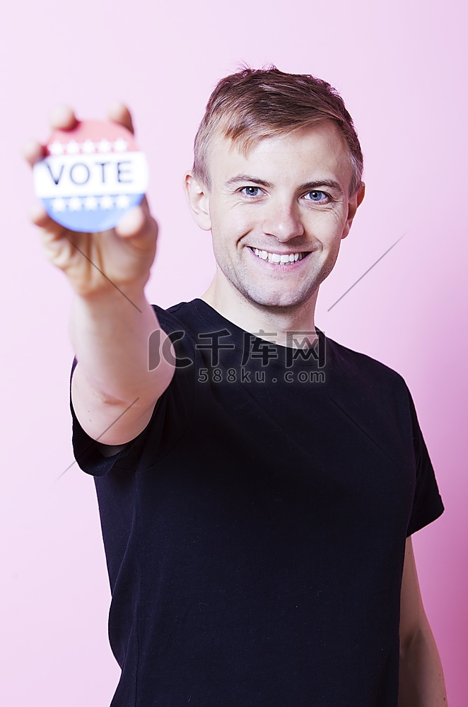 粉色背景下，一名年轻人手持投票
