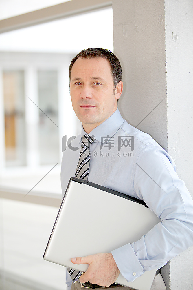一名商人拿着笔记本电脑站在大厅