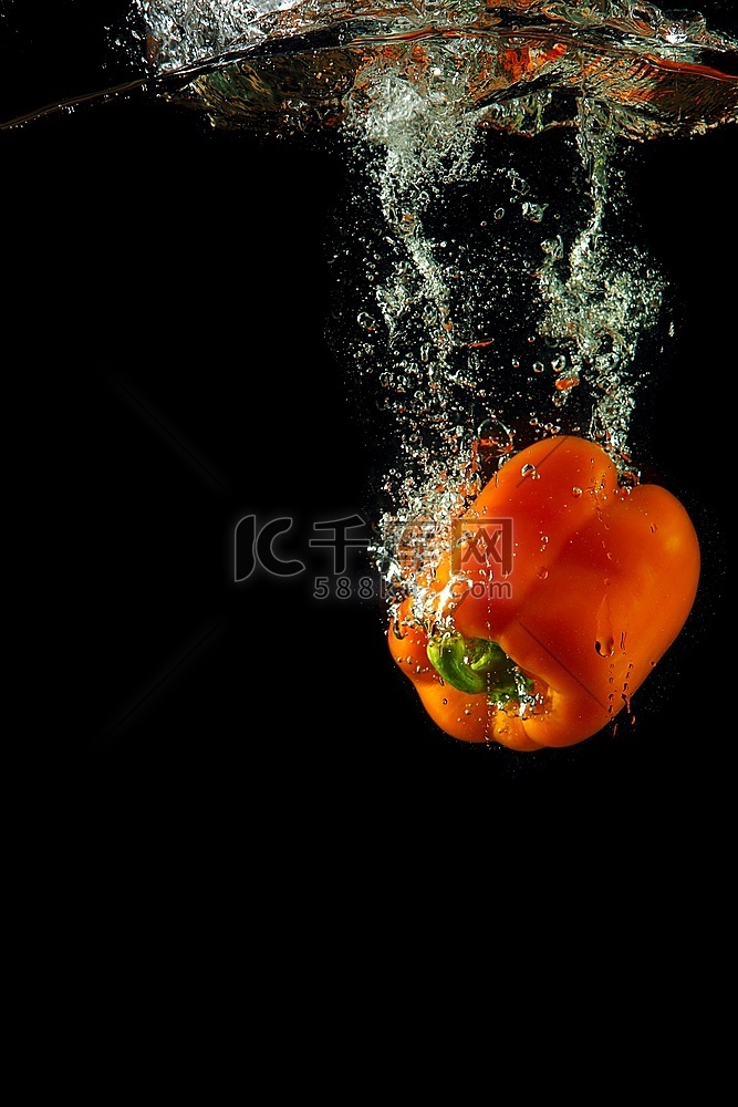 彩色橙色辣椒在黑色背景上溅起水