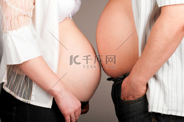 男人和孕妇露出他们的肚皮，侧视