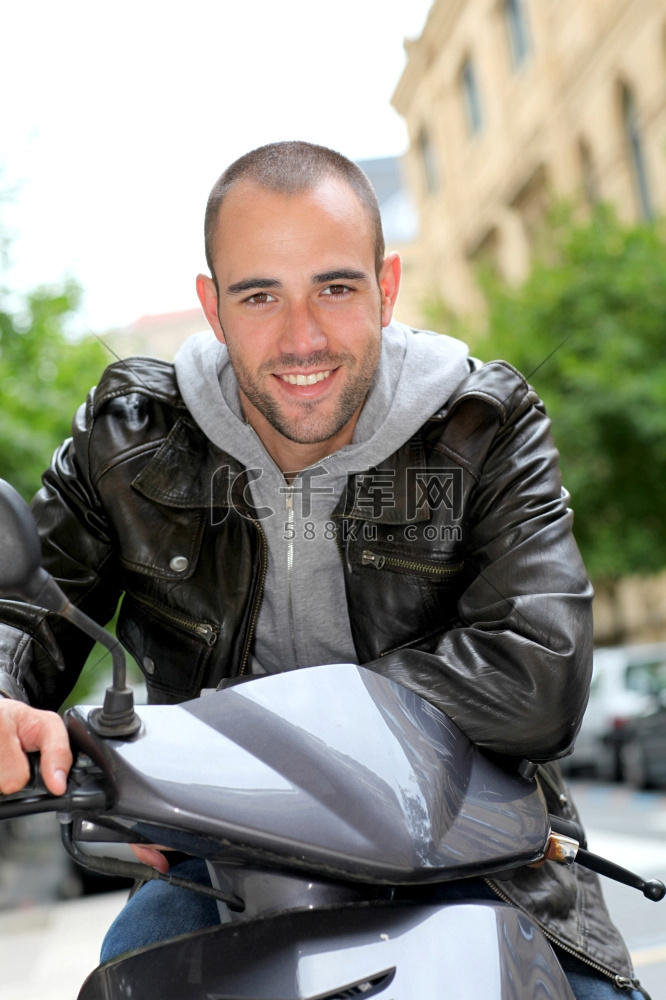 肖像的年轻人坐在摩托车在城里