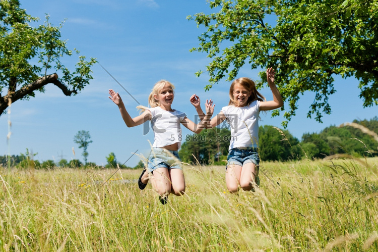 快乐的孩子们在夏天的草地上跳得