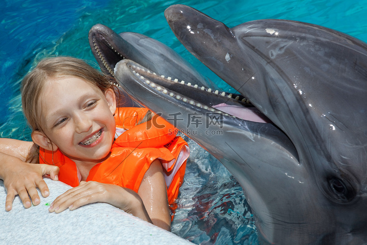 小女孩的欢笑与两只海豚在游泳池