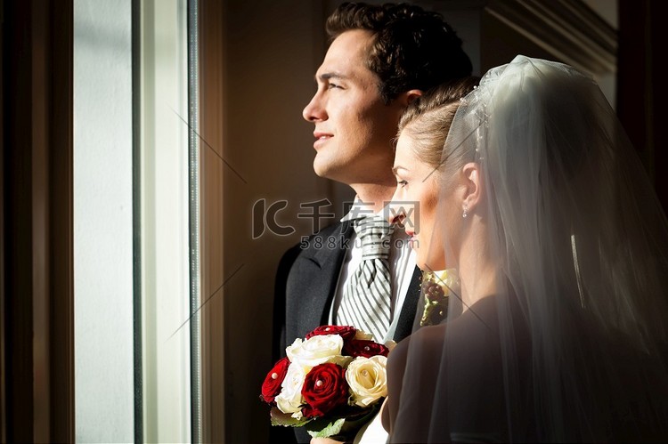 新娘夫妇站在窗口在他们的婚礼和