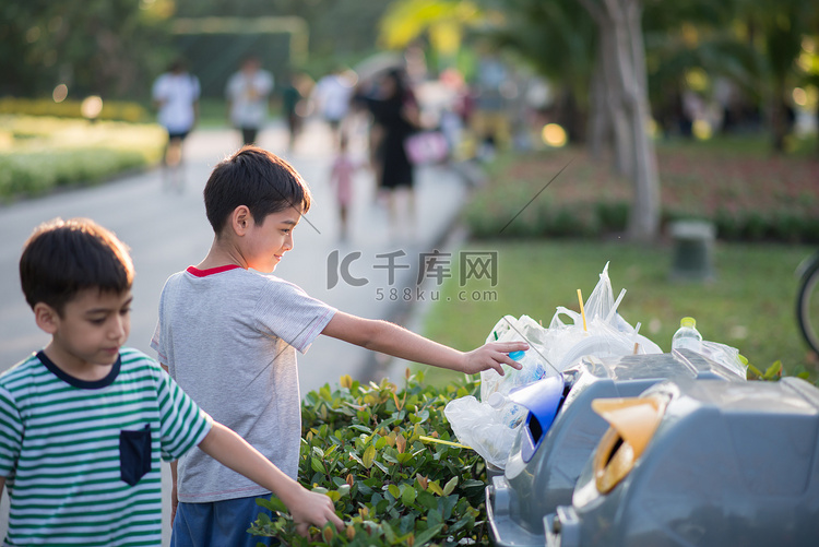 以垃圾到垃圾桶在公园里的小男孩