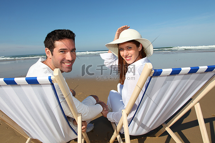 在海滩上坐在长椅上的一对夫妇