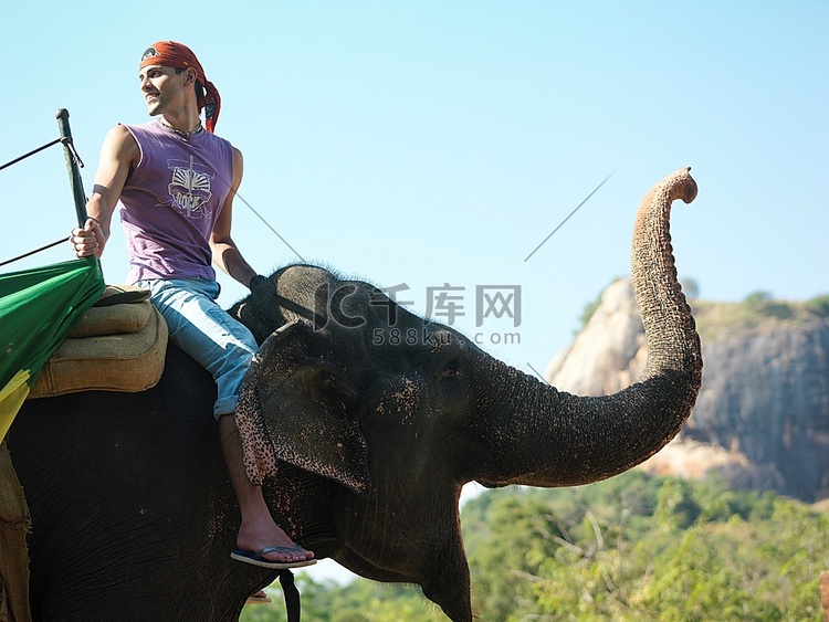 骑着大象侧视的年轻人在背景中俯