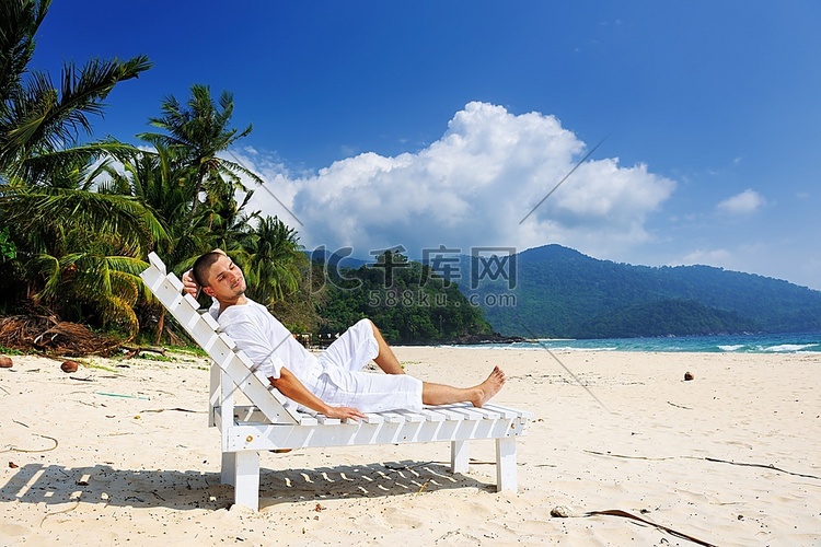 一名白衣男子在热带海滩上放松