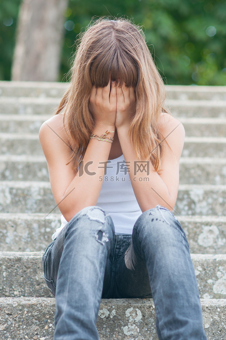 悲伤的十几岁的女孩独自坐在楼梯