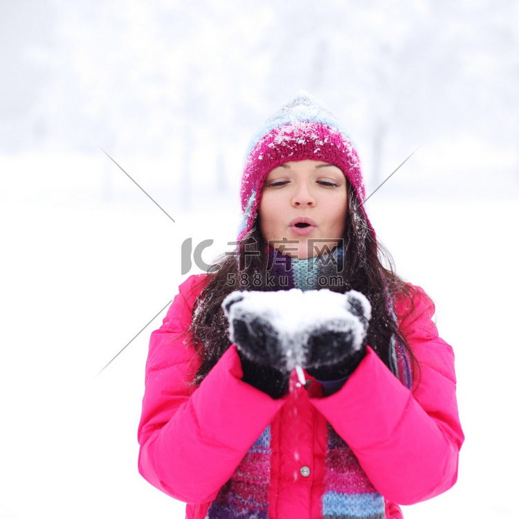 冬天的女孩在手中吹着雪
