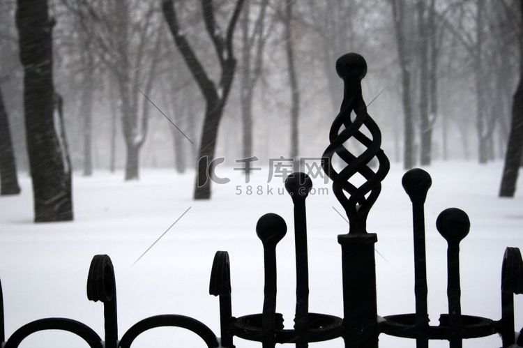 白雪覆盖的公园背景上的锻铁栅栏