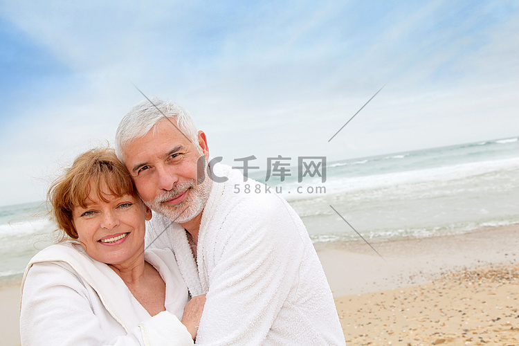 高级夫妇在海滩与水疗浴袍